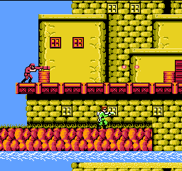 Bionic Commando: the commando in green hangs from a yellow brick building while an enemy fires from a balcony above