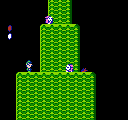 Super Mario Bros. 2: Luigi climbs a stack of green wavy hills past two Shy Guys, with the life meter at upper left